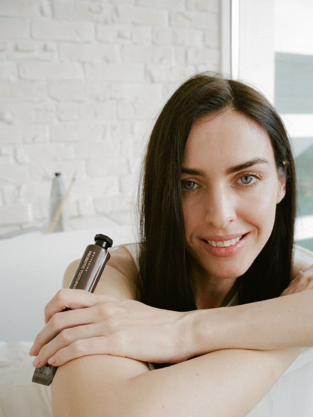 Woman holding INOPRO foam mouthwash beside a bathtub