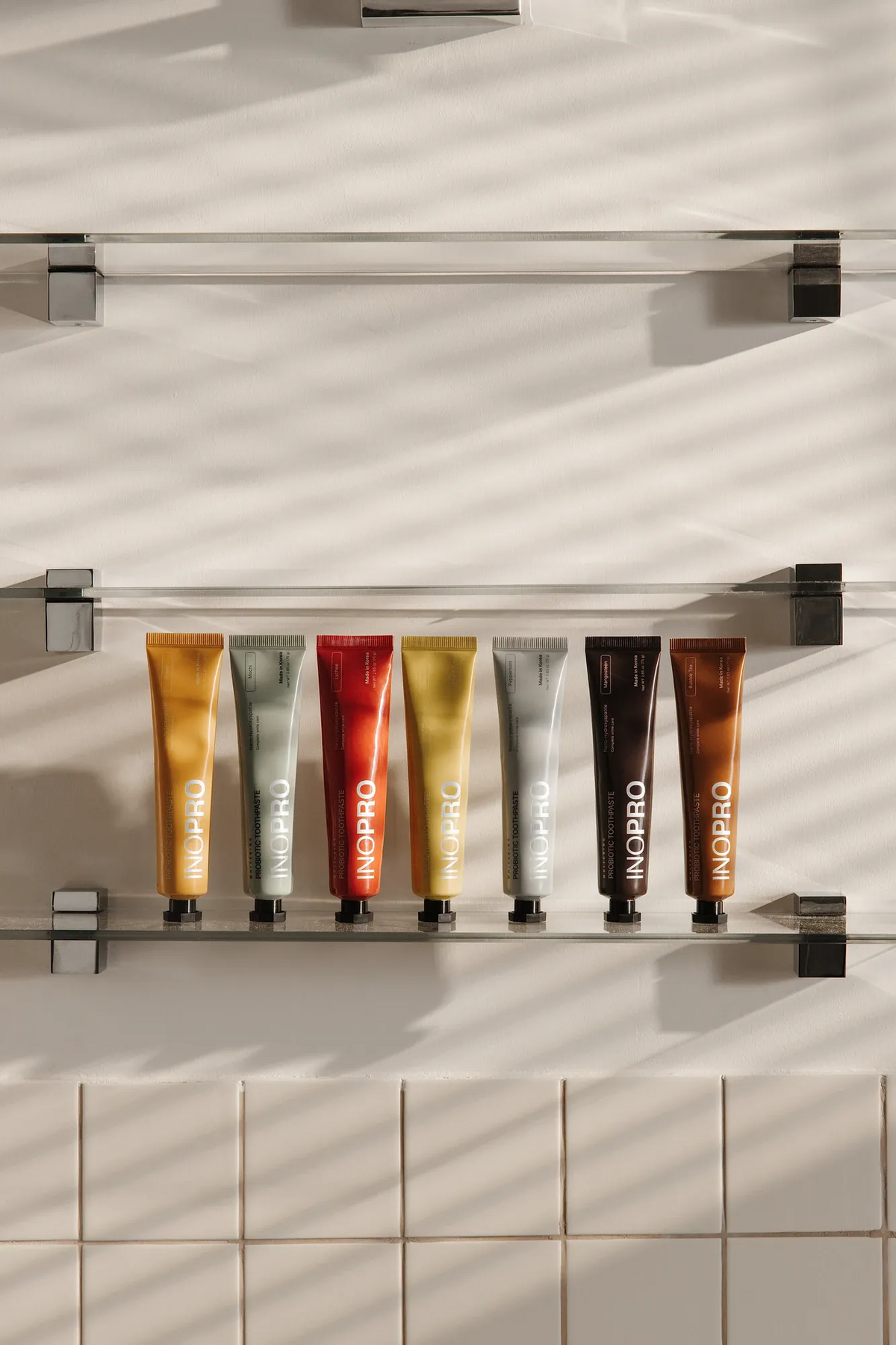 Seven INOPRO toothpaste flavors on a bathroom shelf