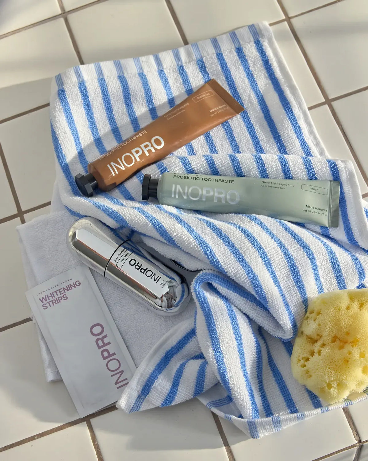 INOPRO toothpaste, foam and whitening strips on a striped towel