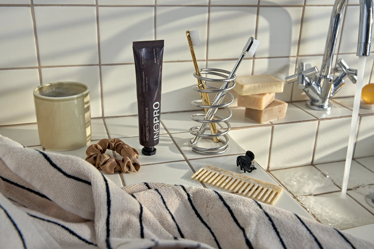 INOPRO toothpaste and toothbrushes beside a sunlit bathroom sink