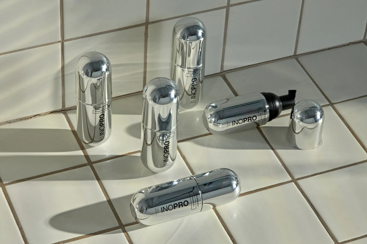 Silver INOPRO foam mouthwash bottles on sunlit bathroom tiles