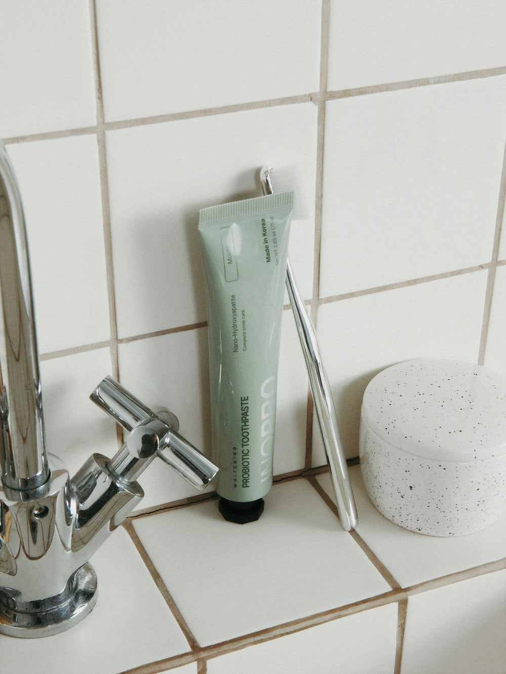 INOPRO toothpaste and a toothbrush beside a bathroom faucet